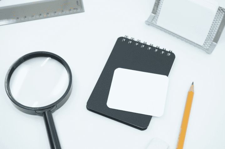 a magnifying glass, a pencil, and a notepad on a table