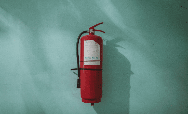red fire extinguisher against a cyan wall
